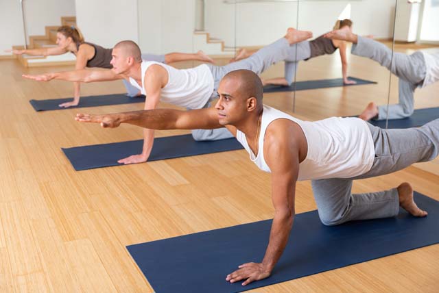 Middle age handsome sportman sitting on mat doing stretching yoga